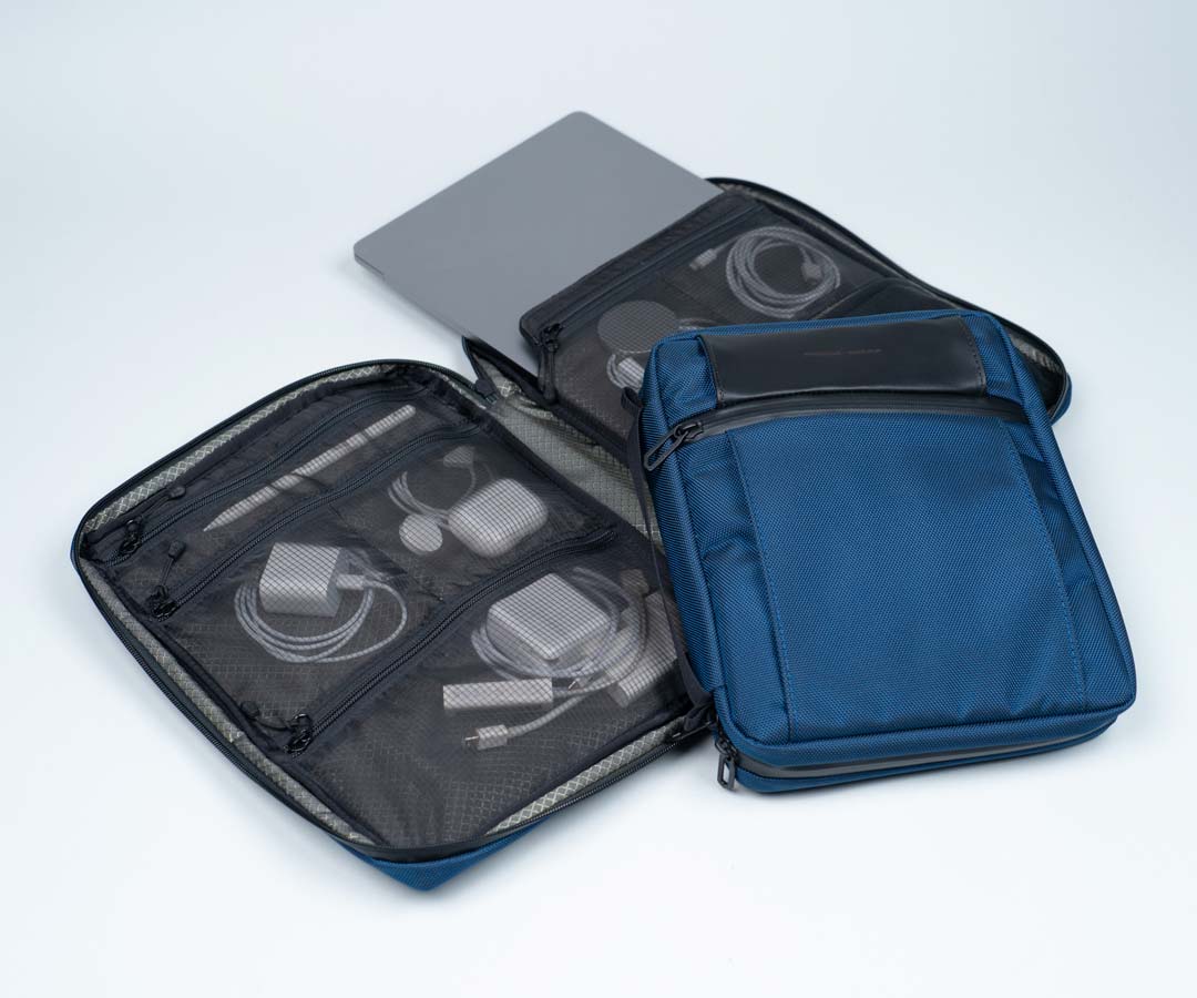 Open travel pouch displaying organized cords, charger and accessories in mesh compartments